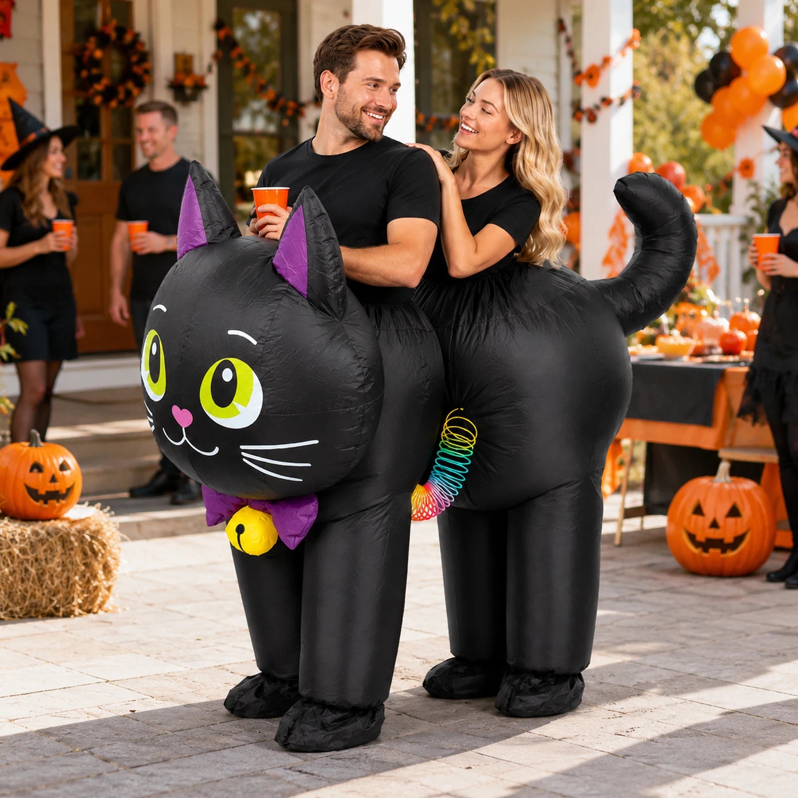 Two adults wear the linked black cat inflatable costume together at a Halloween party.