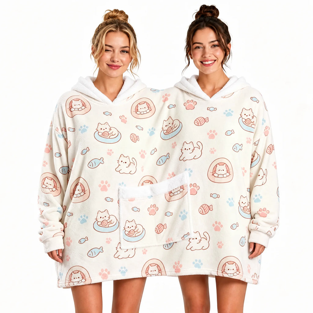 Two adults sharing a cream cat print oversized hoodie blanket with twin hoods and a shared front pocket.
