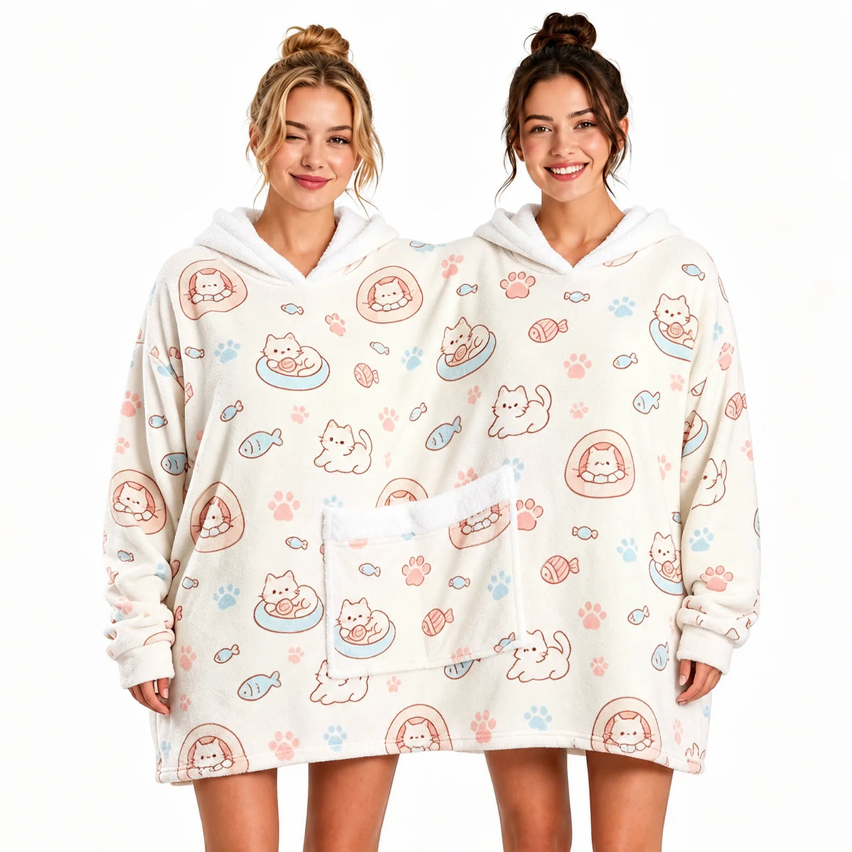 Two adults sharing a cream cat print oversized hoodie blanket with twin hoods and a shared front pocket.