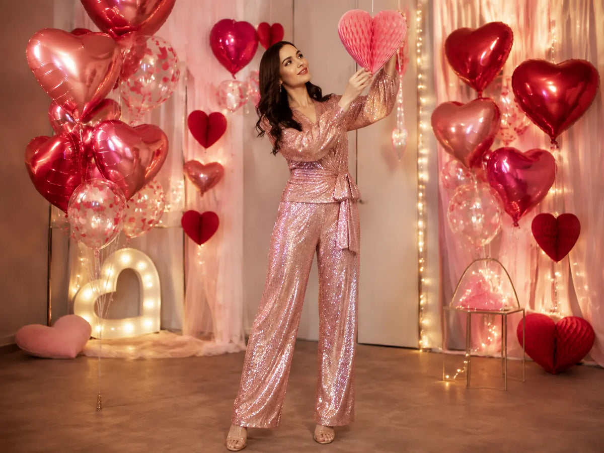Woman in a pink sequin outfit styling heart decorations for Valentine's Day