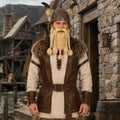 Man wearing a brown horned Viking helmet and blonde beard in a village setting
