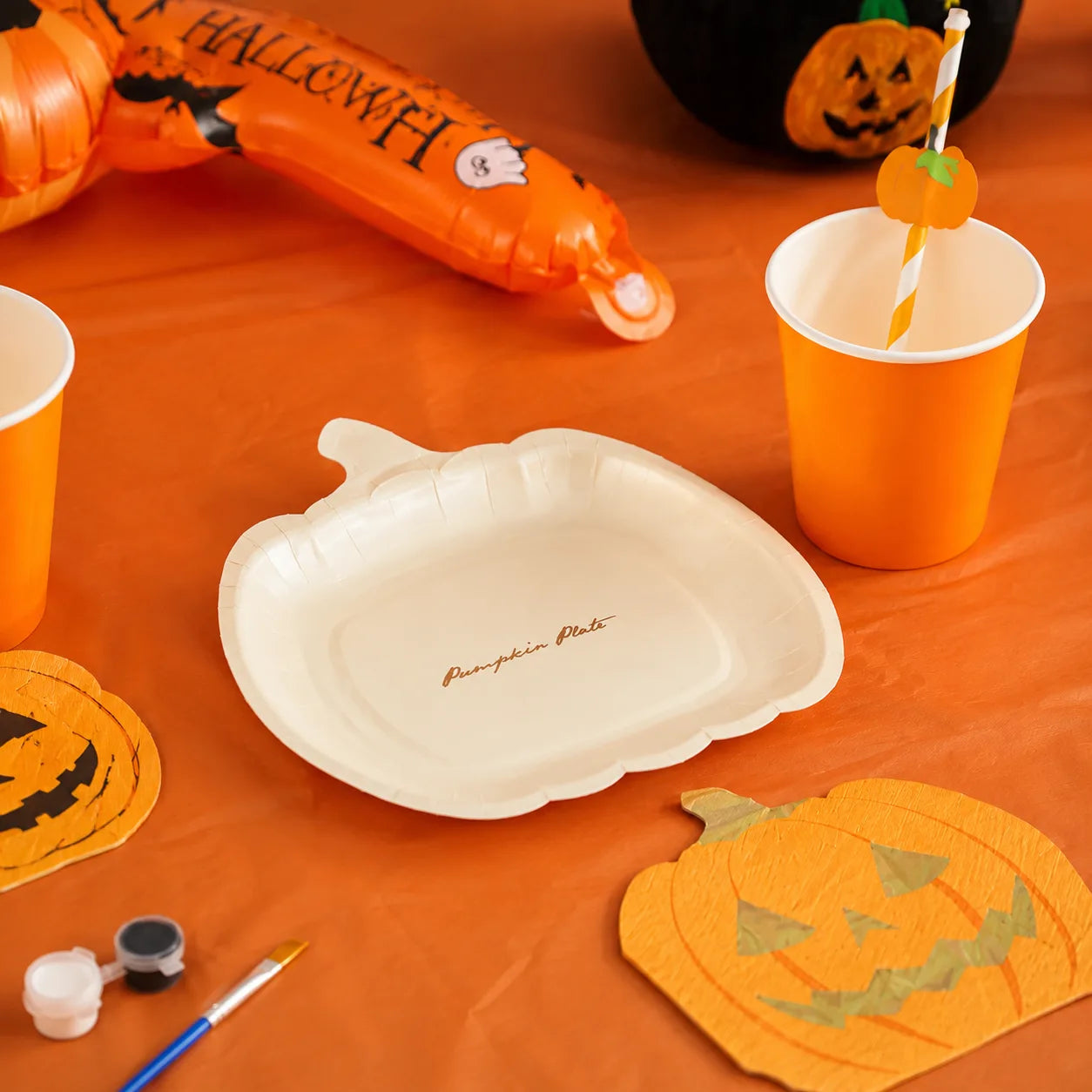 White pumpkin plates with orange cups, pumpkin straws, pumpkin napkins and Halloween tableware for a pumpkin farm party setup