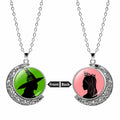 Silver moon pendant necklace with green witch silhouette on the front and pink princess silhouette on the back.